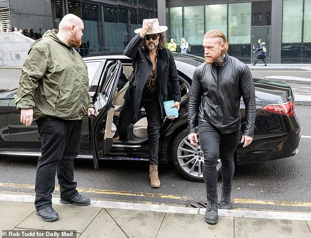 Russell Brand Arrives at Court for Rape Charges in Dramatic Attire and Bible Incident